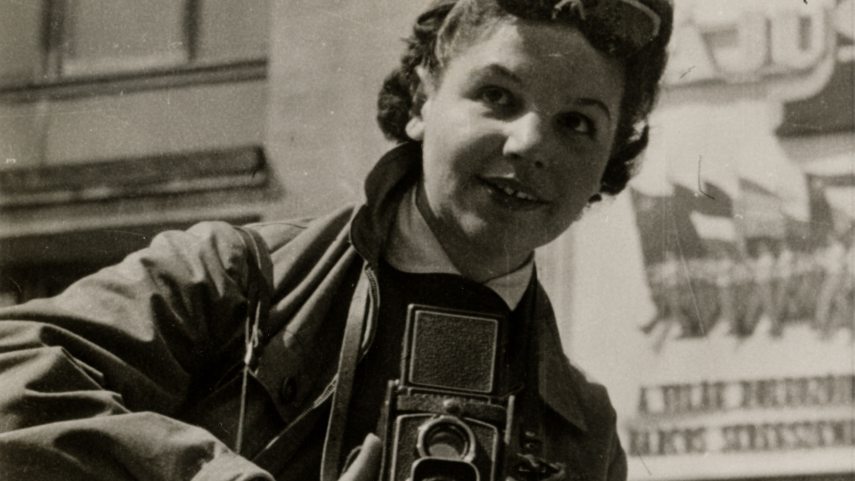 Ács Irén a munka ünnepén egy felvonulást fotóz. 1959. május 1. Ismeretlen felvétele.jpg